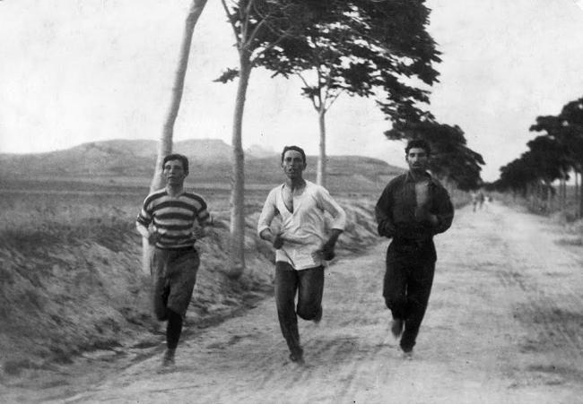 1896OlympicMarathon: Three athletes in training for the marathon race of the 1896 Athens Olympic Games, on the road from Marathon, Greece, Charilaos Vasilakos in the middle. Sources:Wikipedia