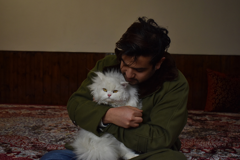 Tahir sits with his cat, Snowbear on Jan. 12, 2022. in Kashmir, India. (Photo by Amir Bin Rafi)