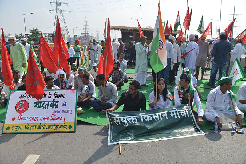 Farmers sitting on NH9 at Ghazipur border during Bharat Bandh called by Sanyukt Kisan Morcha (SKM) against new farm laws, in New Delhi on Monday. UNI PHOTO-PSB6U