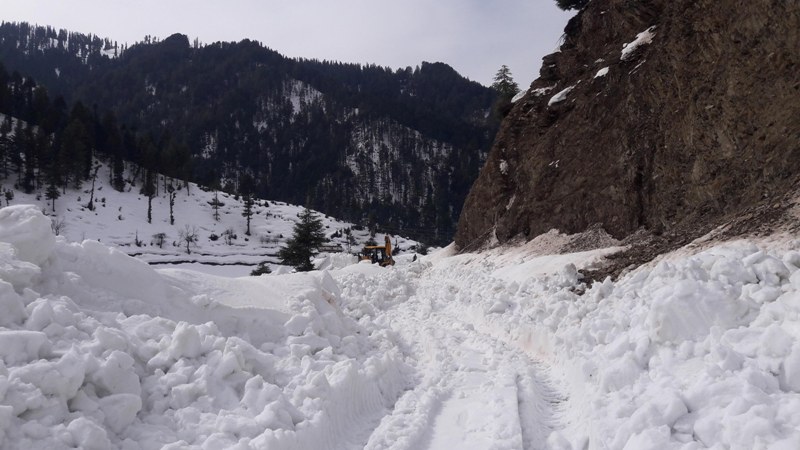 People walk through snow covered Bhaderwah-Chamba inter-state road in Kashmir