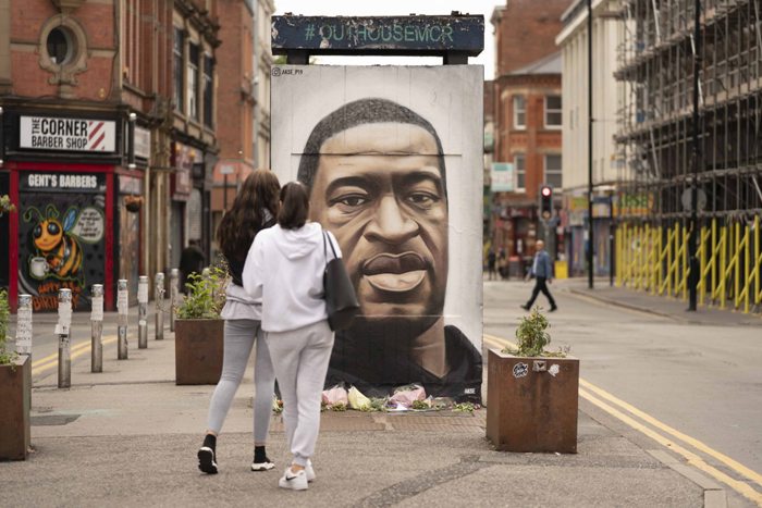 People gather by a mural of George Floyd in UK's Manchester