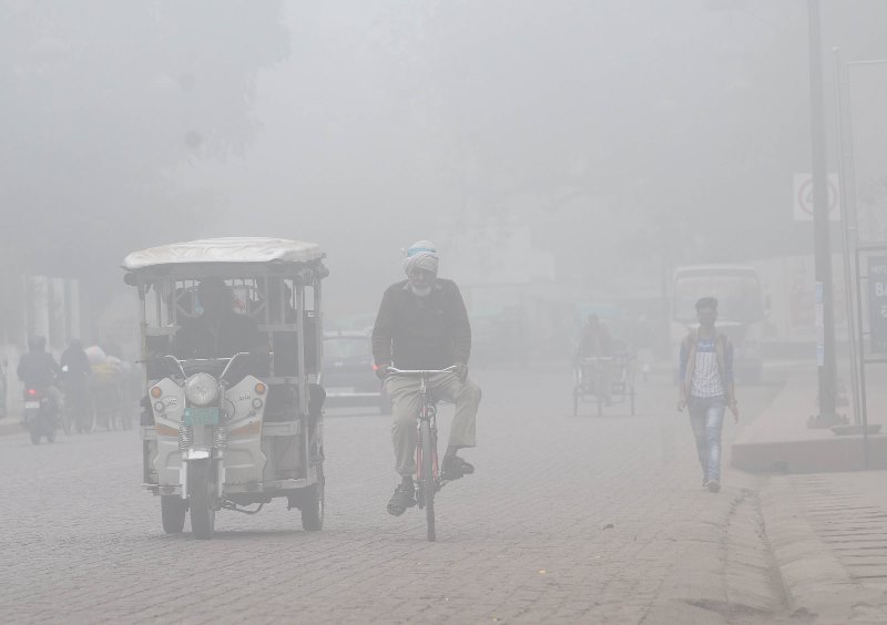 A man cycles in a fog covered morning in Lucknow