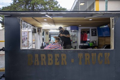 Mexican barber Gerardo (R) gives a haircut to a customer