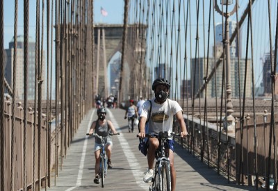 New York: People wearing face masks ride on Brooklyn Bridge