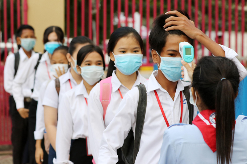 Students queue for body temperature screening at the Bak Touk High School in Phnom Penh