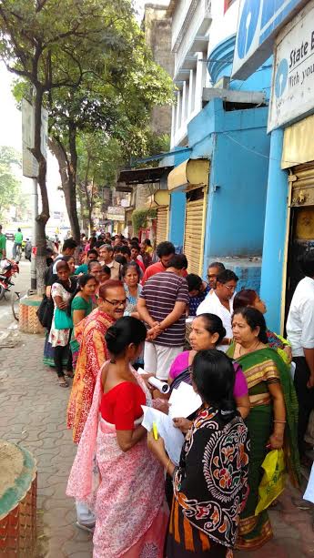 People stand in queue to exchange currency notes