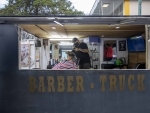 Mexican barber Gerardo (R) gives a haircut to a customer