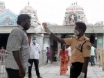 A security personnel monitor body temprature of a devotee before entering into Kapaleeswarar Temple