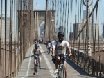 New York: People wearing face masks ride on Brooklyn Bridge