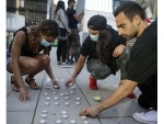 Participants arrange candles during a vigil in front of the Vancouver Art Gallery