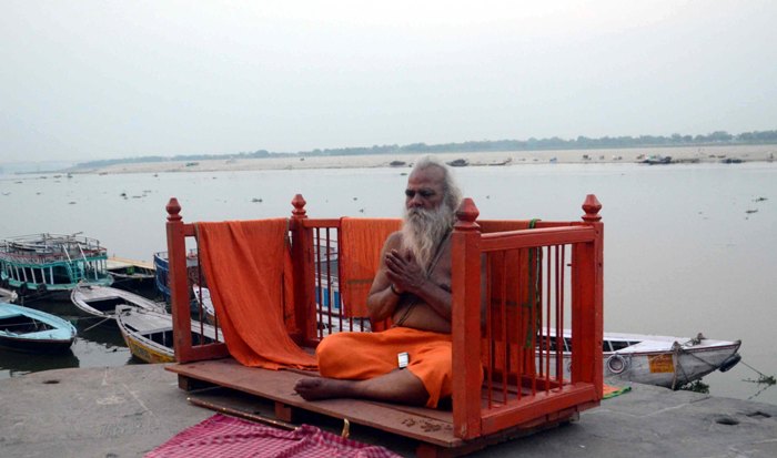 Sadhu meditates on banks of holy river of Ganges in Varanasi 