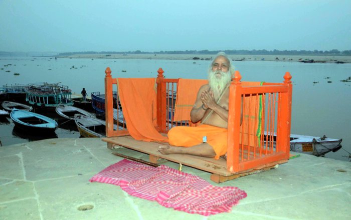 Sadhu meditates on banks of holy river of Ganges in Varanasi 