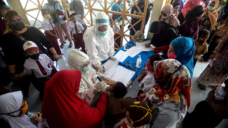 Indonesia: A health officer checks condition of an elementary student before giving a MR vaccine