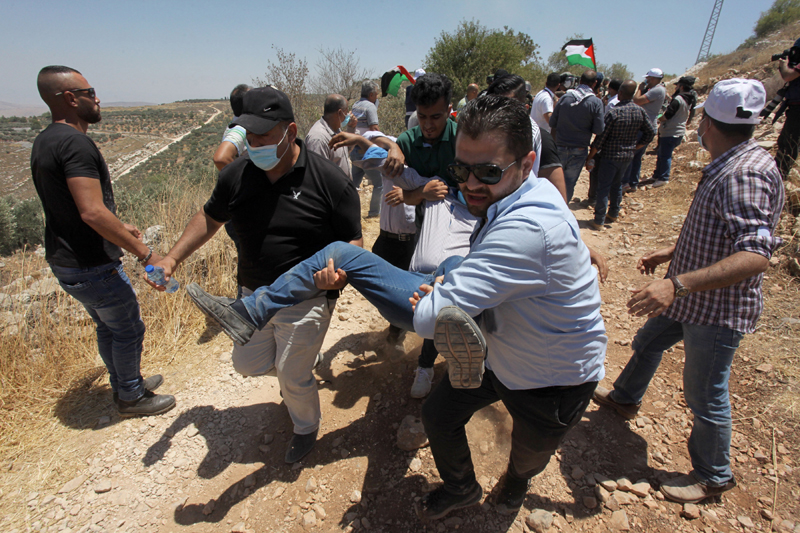 Palestinian protesters carry an injured man during clashes with Israeli soldiers