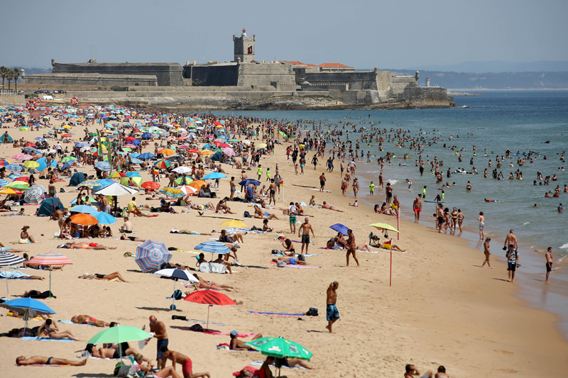Portugal: Beachgoers sunbathe and swim in Carcavelos beach
