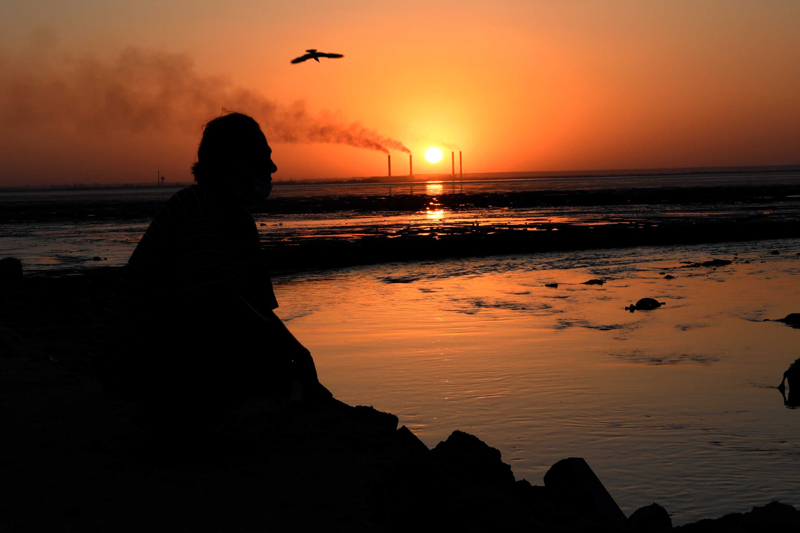 A local resident sits on the beach during sunset in Kuwait City