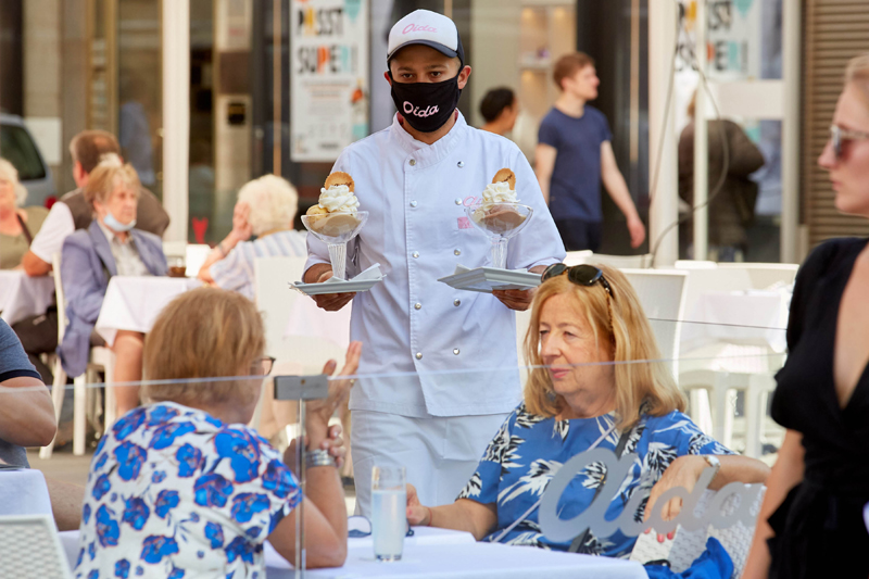 A waiter wearing a face mask serves a table at a restaurant in Vienna