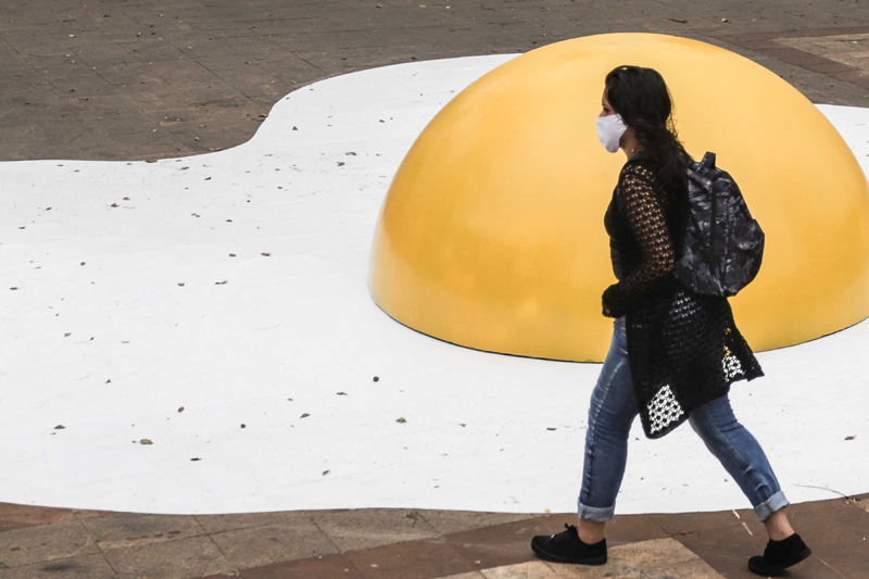 Pedestrian wearing mask walks by artwork in Sao Paolo