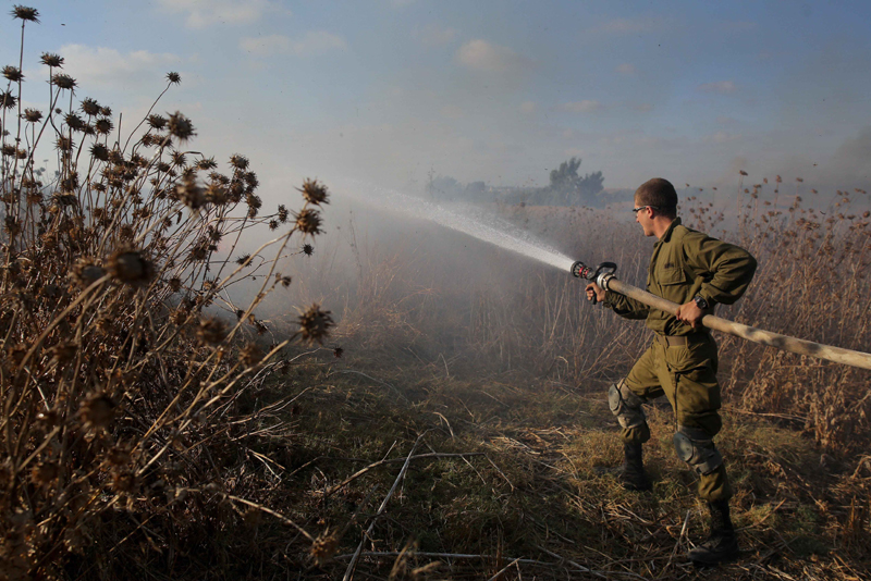 Israeli soldier tries to extinguish fire caused by explosive balloon