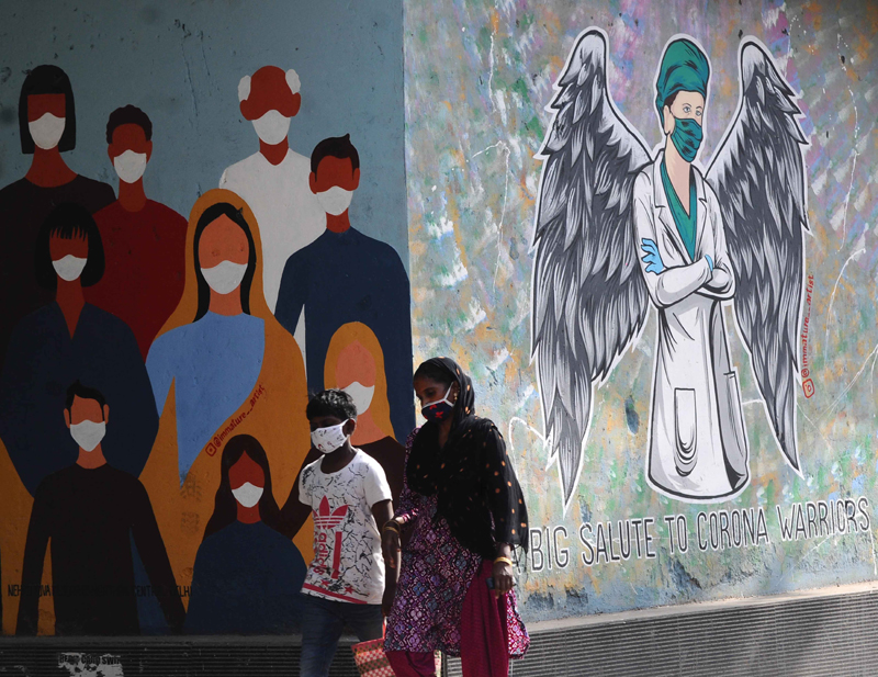 New Delhi: People walk past wall painting saluting COVID warriors