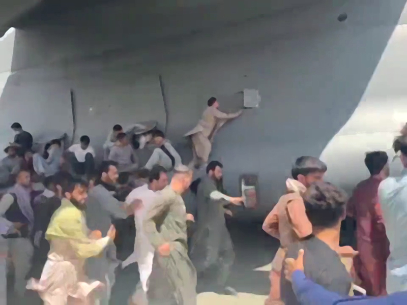 People climbing on a US Air Force aircraft at Kabul airport
