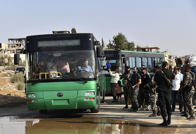 Local armed men are seen on buses in Daraa