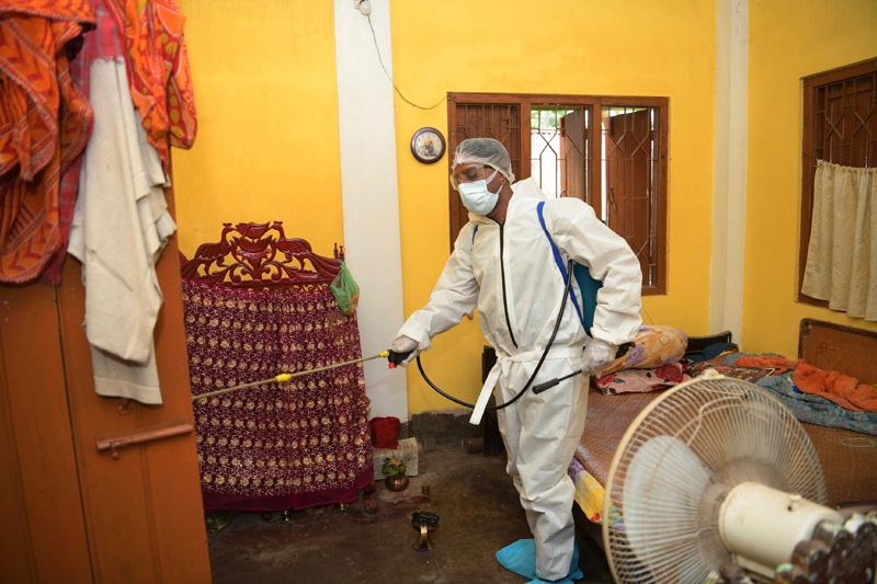 A volunteer sanitizing a house in Agartala